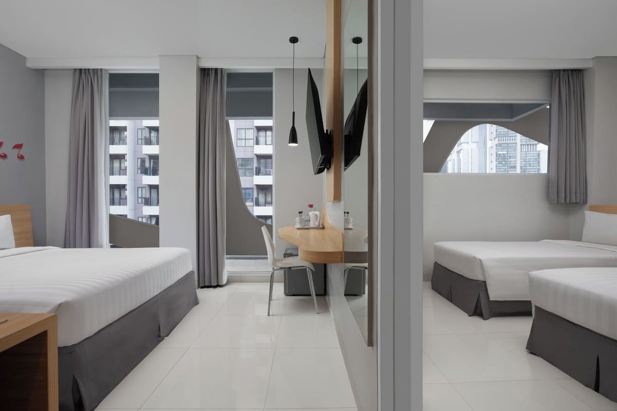 A hotel room with a bed, a desk, a chair, a TV, and a view of the city.