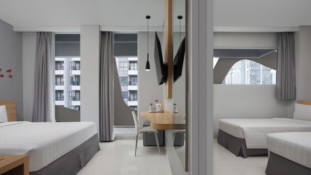 Una habitación de hotel moderna con una cama, un escritorio y vistas a la ciudad.