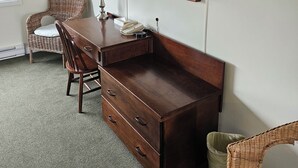 A hotel room with a wooden desk, a chair, a lamp, a telephone, and a television mounted on the wall. - Pacific Rim Motel (Ucluelet)