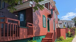 A red and green house with a front porch and a staircase leading to the door. - Auberge Le St-Gab (Saint-Gabriel)
