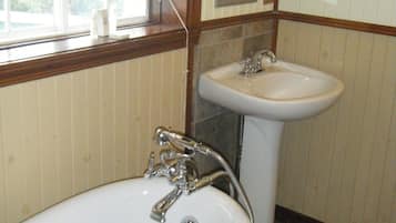 A bathroom with a bathtub, a sink, and a window with a blind.