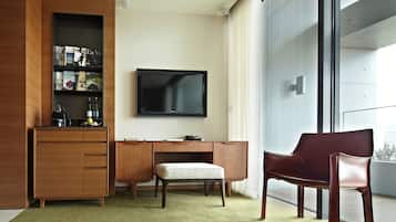 A modern hotel room with a wooden cabinet, a desk, a television, and a red chair.