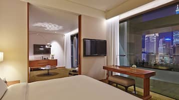 Une chambre d’hôtel équipée d’un lit, d’un bureau, d’une chaise, d’une télévision et offrant une vue sur la ville.