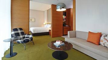 Ein Hotelzimmer mit Bett, einer Couch, einem Sessel, einem kleinen Tisch und einem Bücherregal.