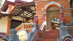 Un escalier orné de sculptures complexes représentant des créatures mythiques, menant à un bâtiment traditionnel doté d’un toit en tuiles et d’une entrée couverte.