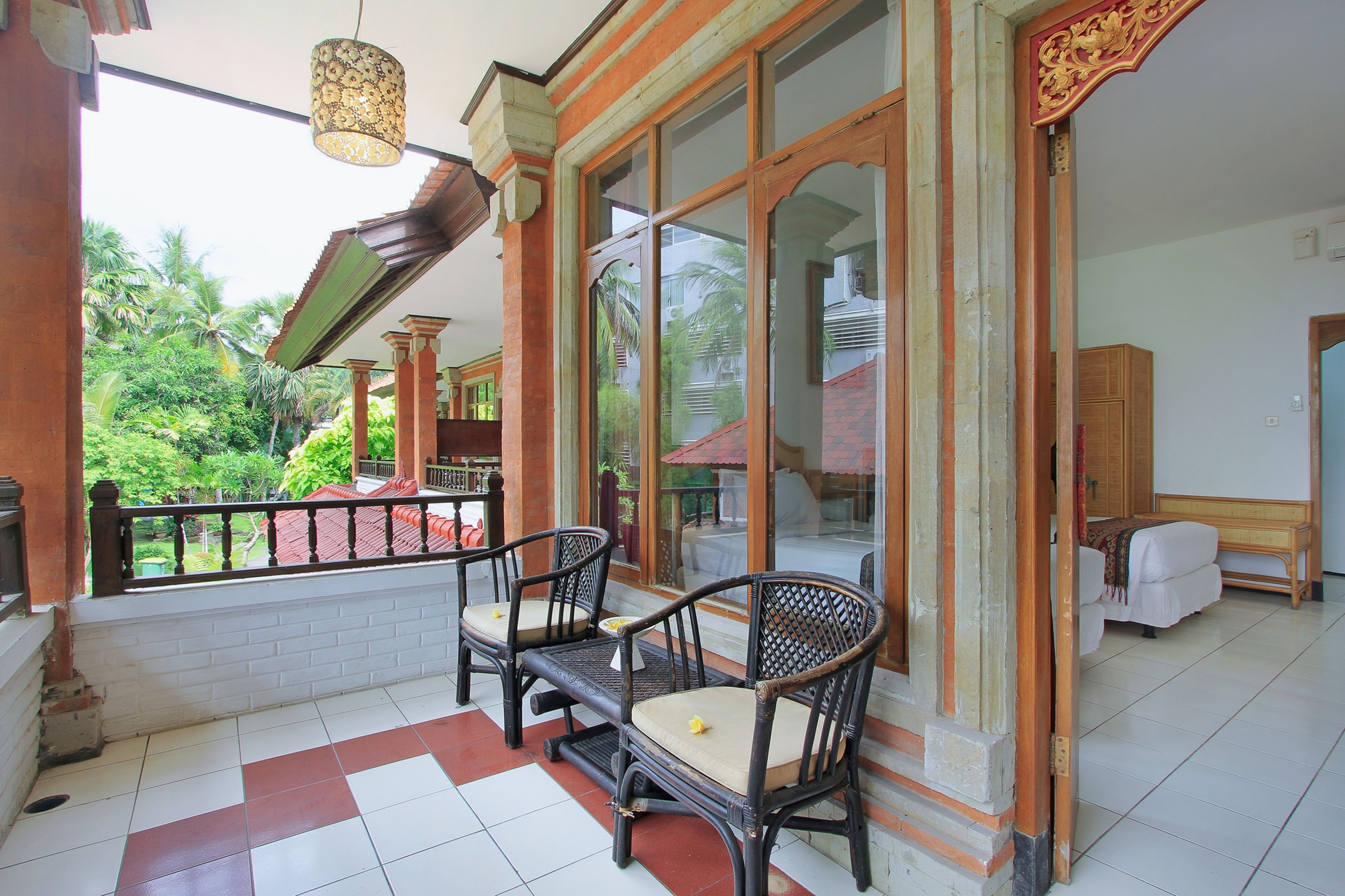 A balcony with two wicker chairs, a wooden table, and a hanging lamp.