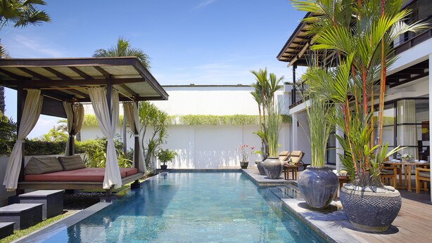 A swimming pool with a covered seating area, potted plants, and a wooden deck. - Temple Hill Residence Villa (Jimbaran)