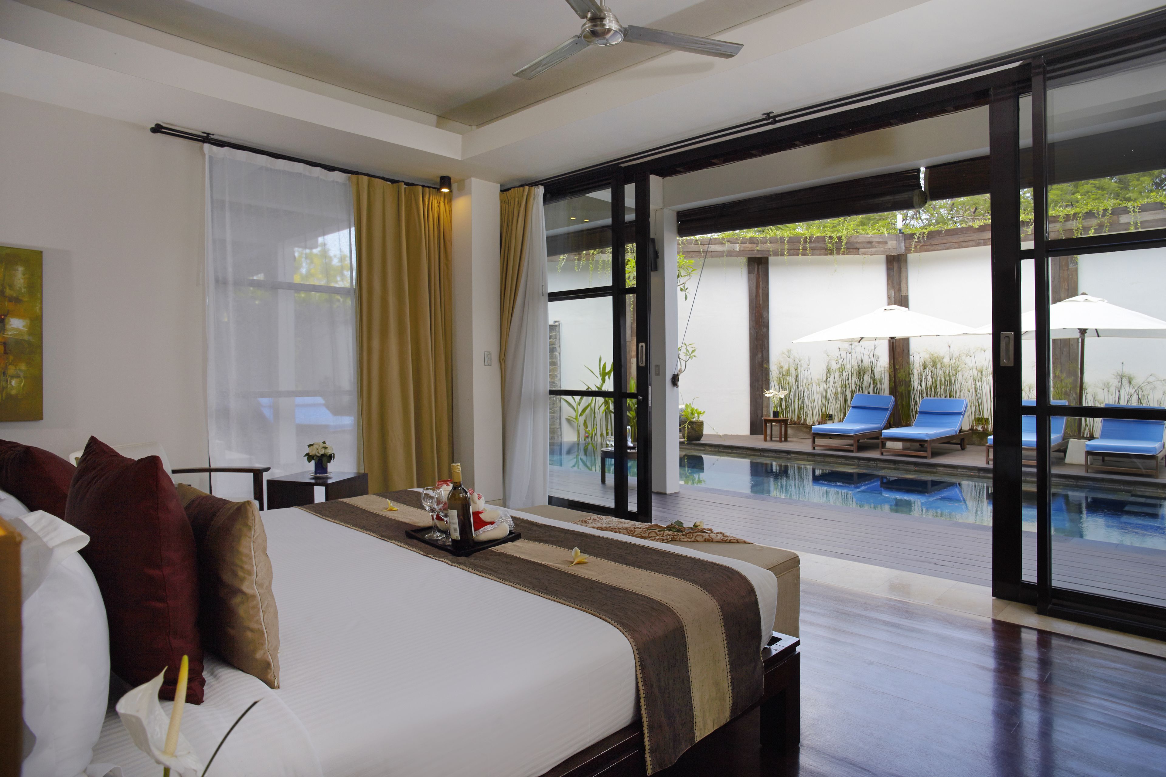Une chambre d’hôtel avec un lit, une vue sur la piscine et une porte-fenêtre coulissante donnant sur l’espace extérieur.