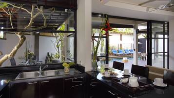 A modern kitchen with a large island, a dining area with a view of a pool, and a glass-enclosed patio.