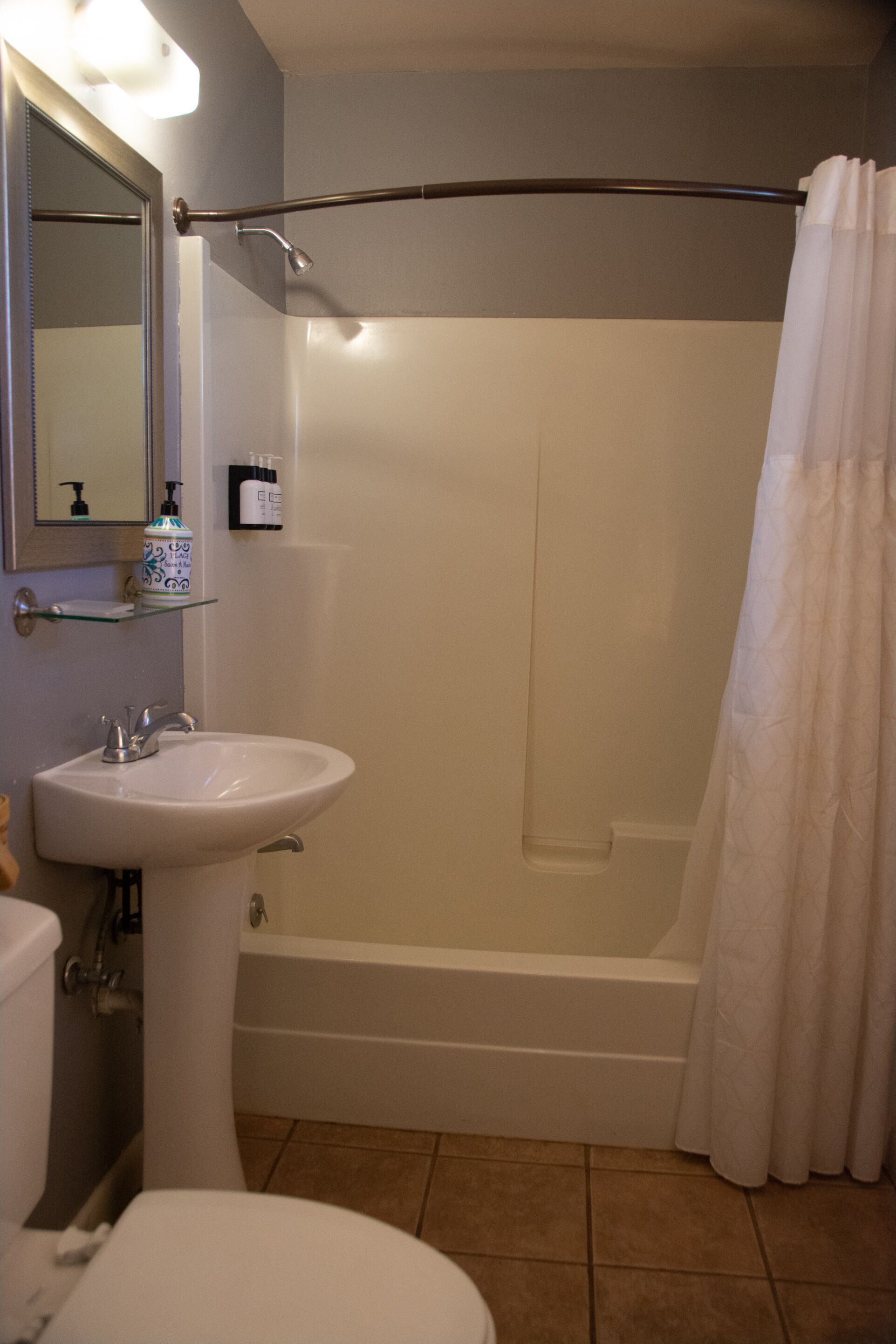 A bathroom with a white sink, mirror, and bathtub.
