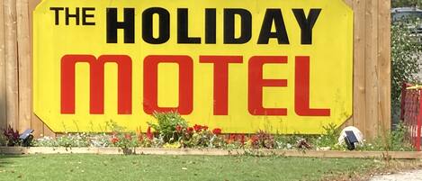 Un letrero amarillo grande con letras negras y rojas que anuncia “The Holiday Motel”.