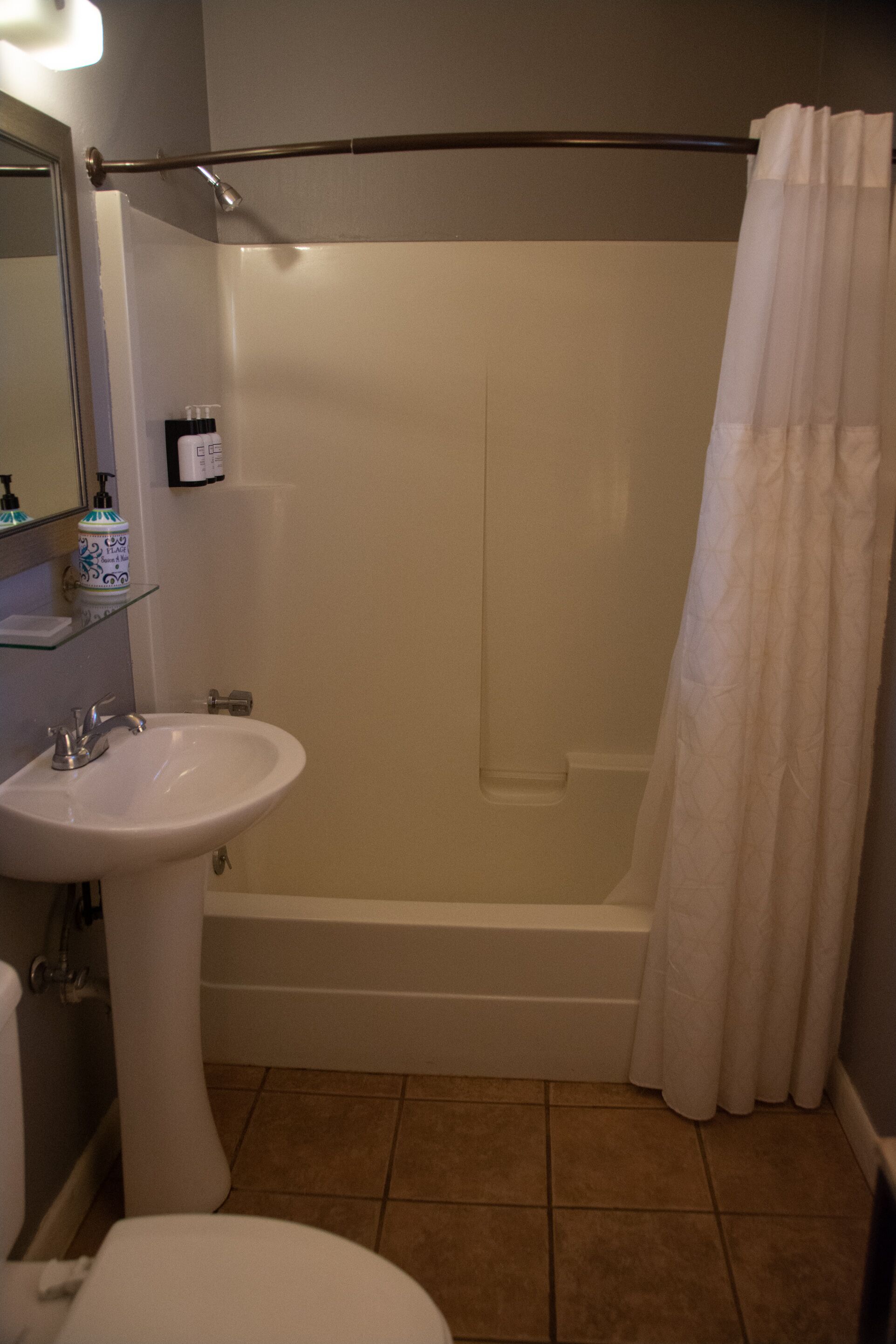Un baño con bañera, cortina de ducha, lavamanos e inodoro.
