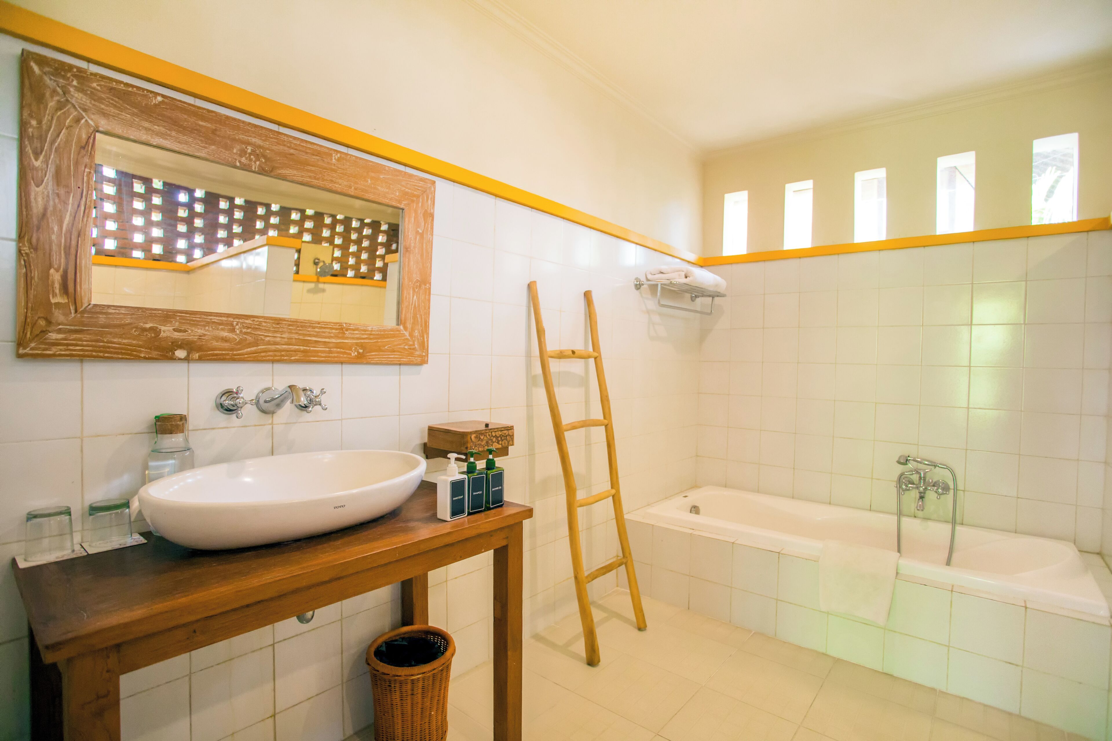 Un baño con tocador de madera, un espejo grande, una bañera y una escalera.