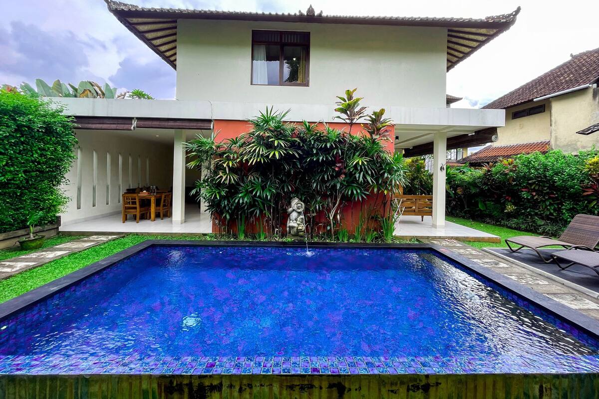 A two-story house with a swimming pool in the front yard.