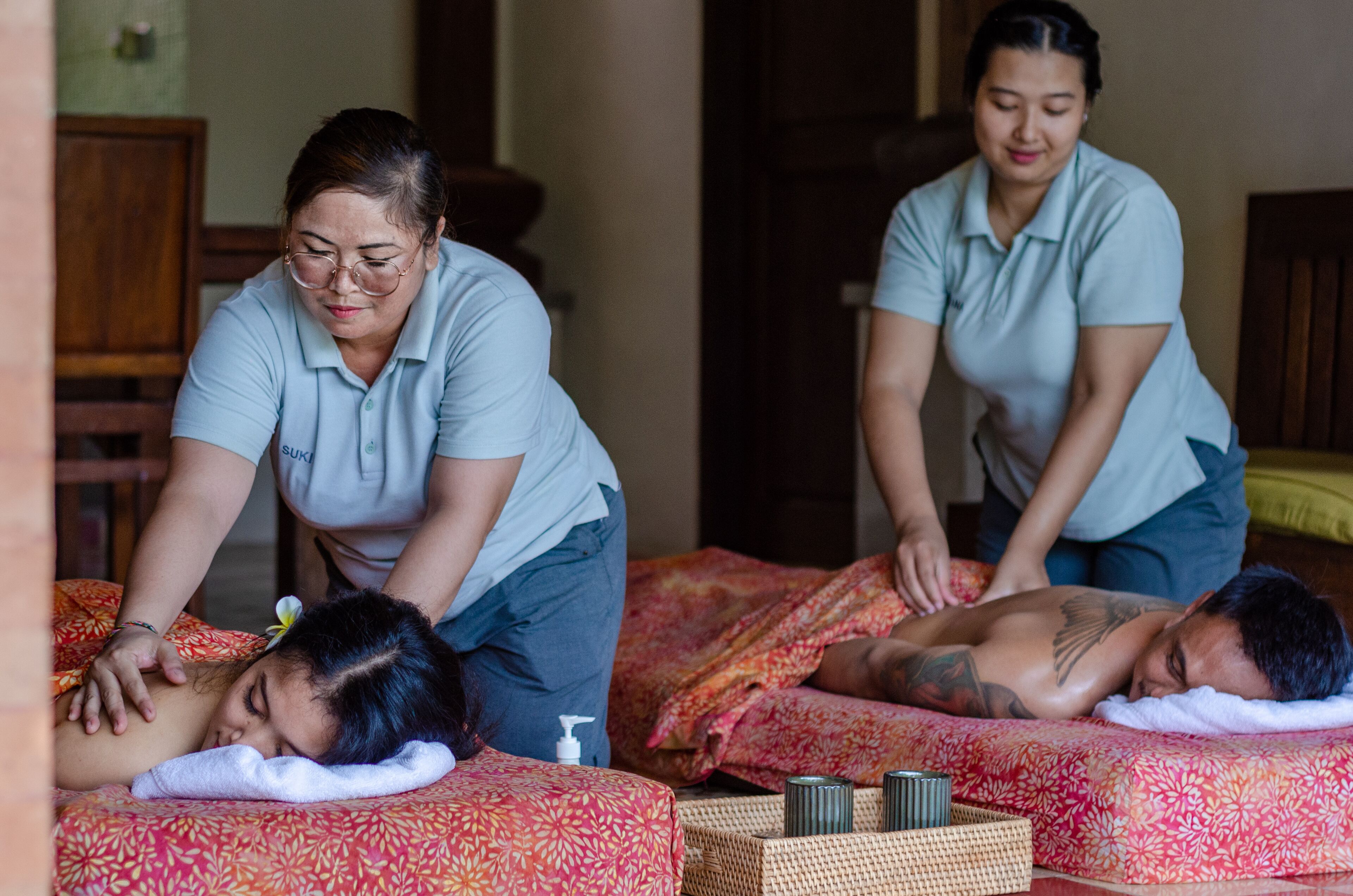 A massage therapy room with two massage tables, one occupied by a client and another by a therapist.