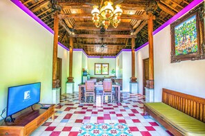 Ein Zimmer mit Schachbrettfußboden, Holzmöbeln, einer Chandelüster und einem Fernseher.
