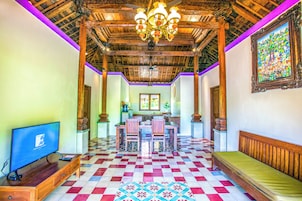 Una habitación con piso a cuadros, muebles de madera, un candelabro y un televisor.