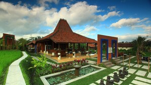 A traditional building with a tiled roof, a garden with a pond, and a seating area with statues. - Ubud Heaven Penestanan (Ubud)