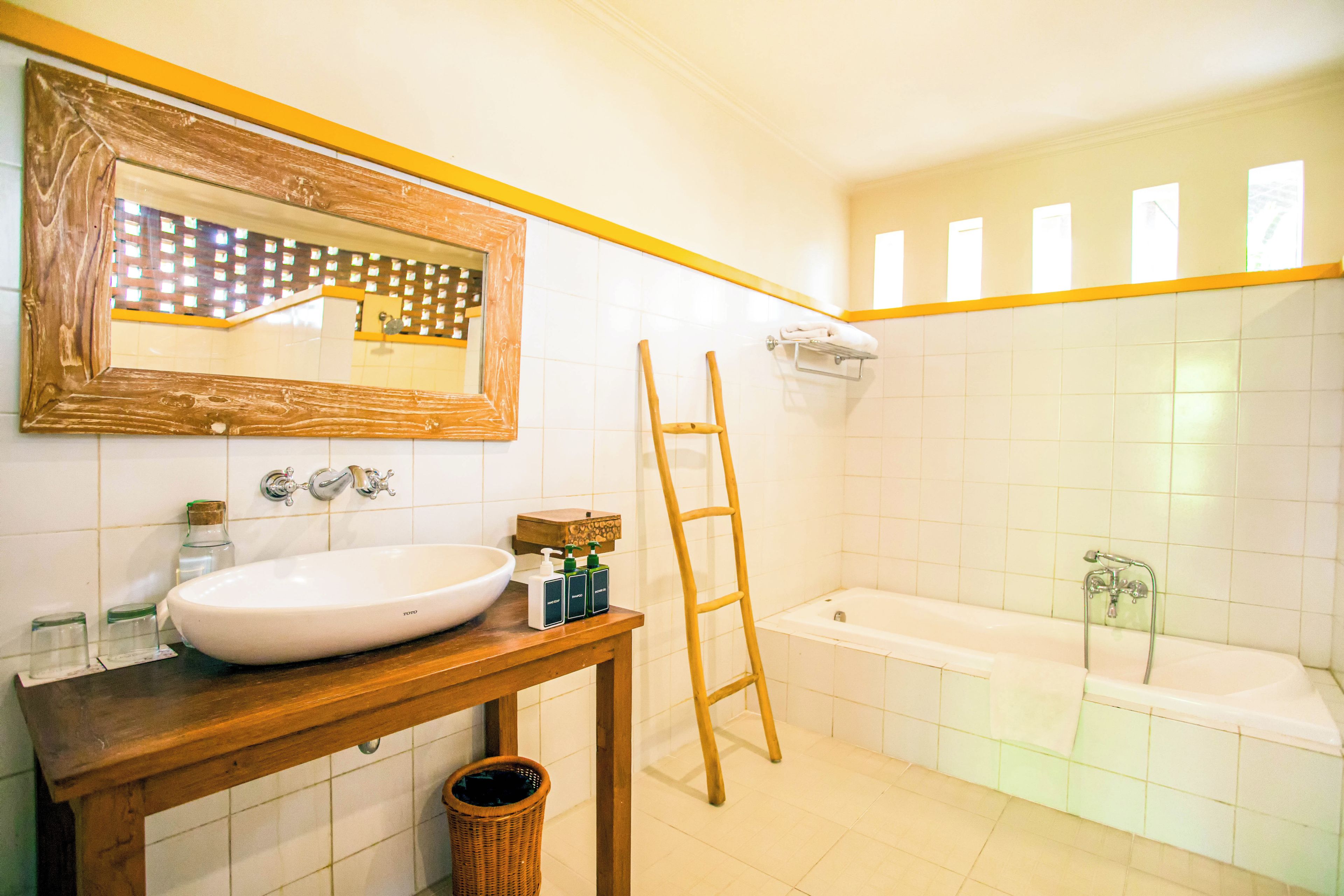 Un baño con tocador de madera, un espejo grande, una bañera y una ventana con vistas.