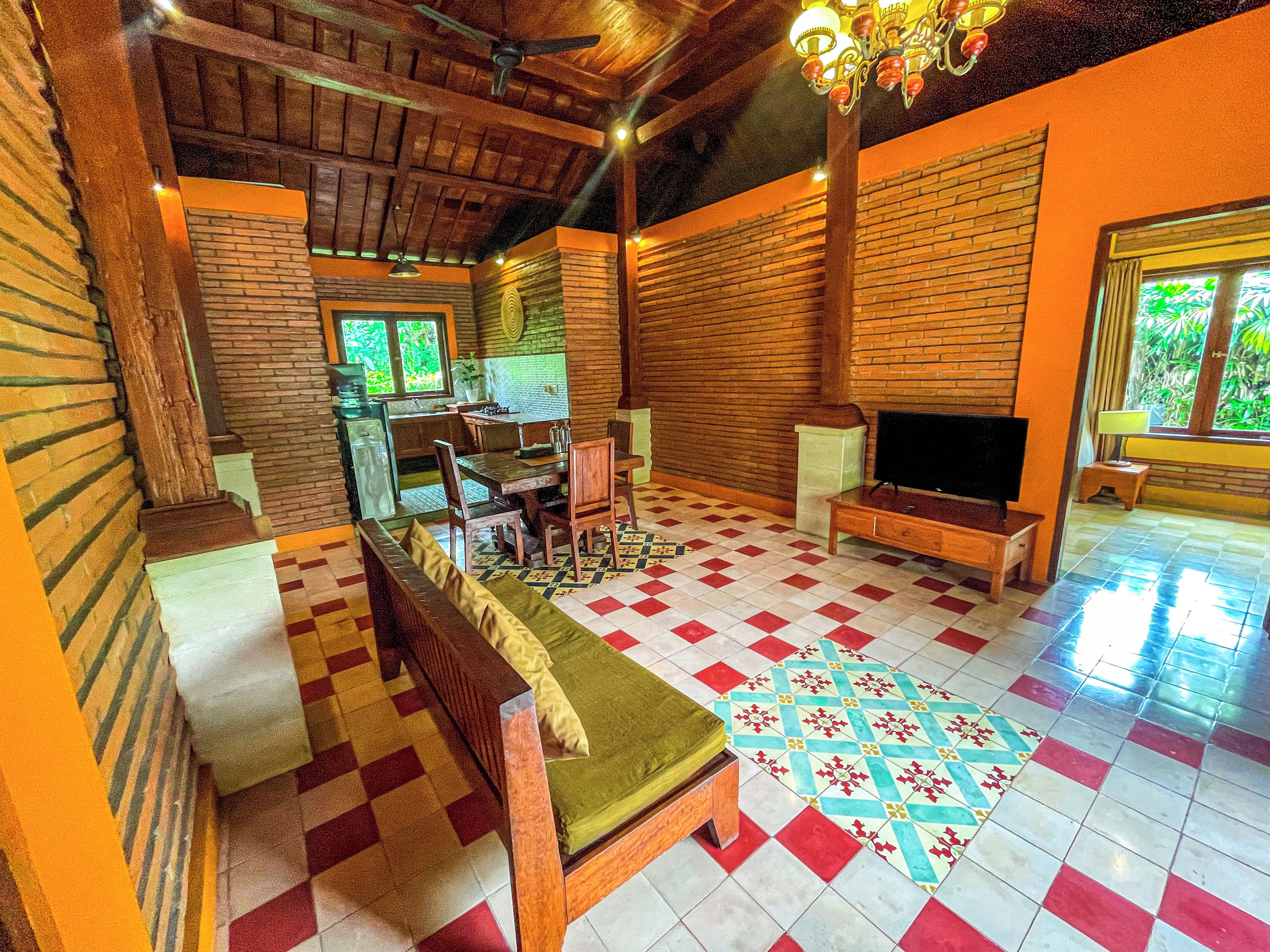 A spacious living area with a wooden ceiling, a television, and a dining table with chairs.