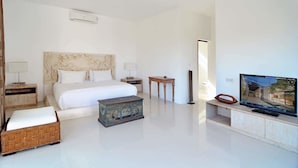 A modern hotel room with a large bed, a television, and a small wooden table. - Scene Estate (Nusa Dua)