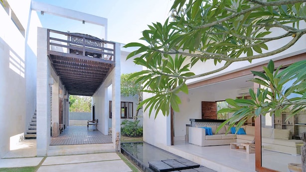 A modern house with a covered outdoor area, a small pool, and a seating area with a sofa and coffee table. - Scene Estate (Nusa Dua)