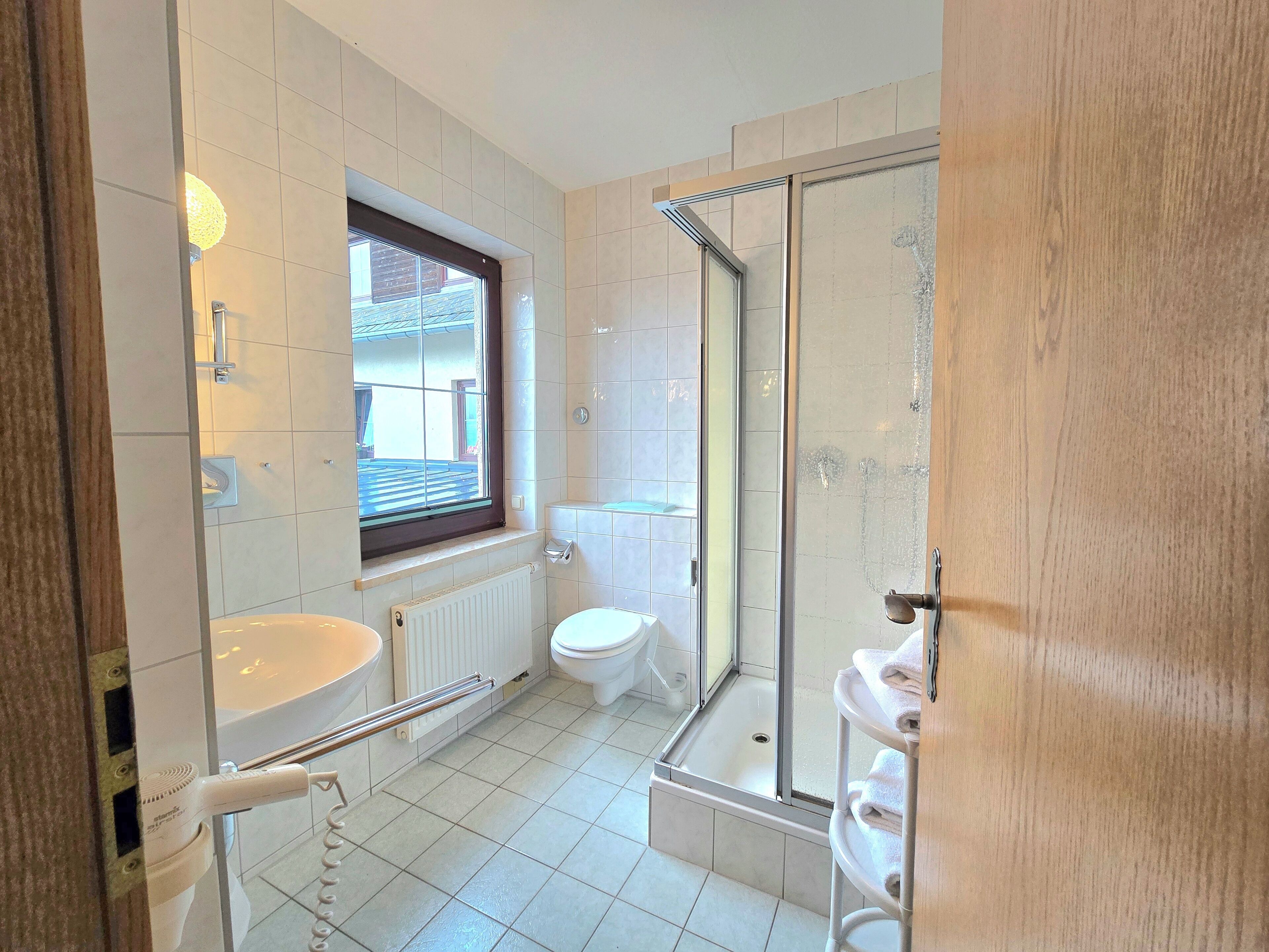 Ein Badezimmer mit Toilette, Waschbecken, Dusche und einem Fenster.