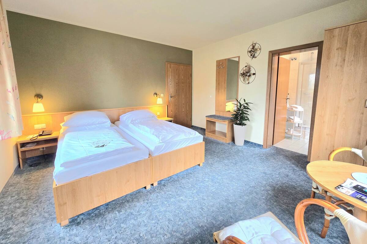 A hotel room with a double bed, bedside lamps, a small desk, a chair, and a mirror.