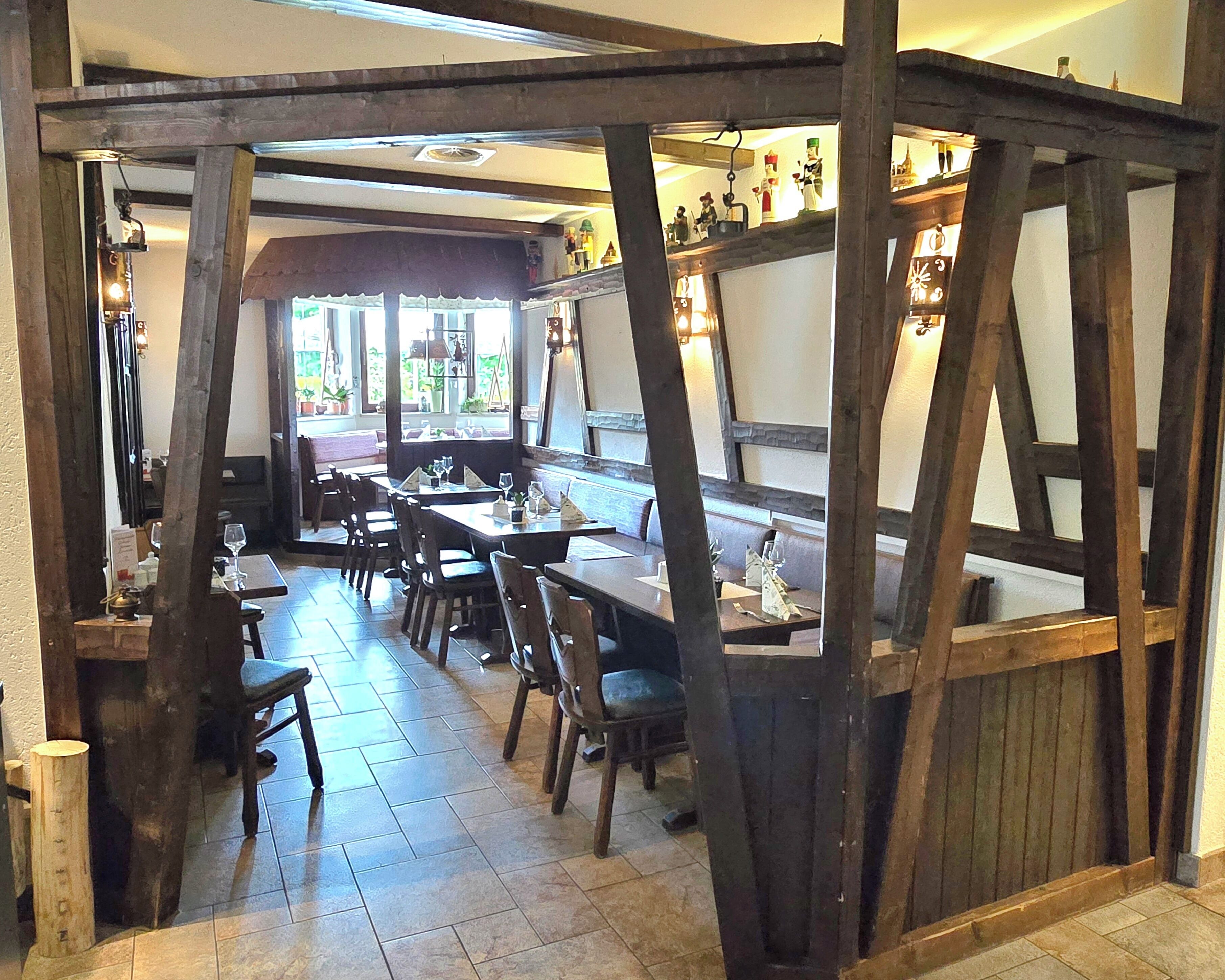 A restaurant with wooden beams, tiled flooring, and tables set for dining.