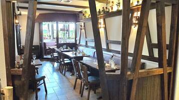 A restaurant with wooden beams, tiled flooring, and tables set for dining.