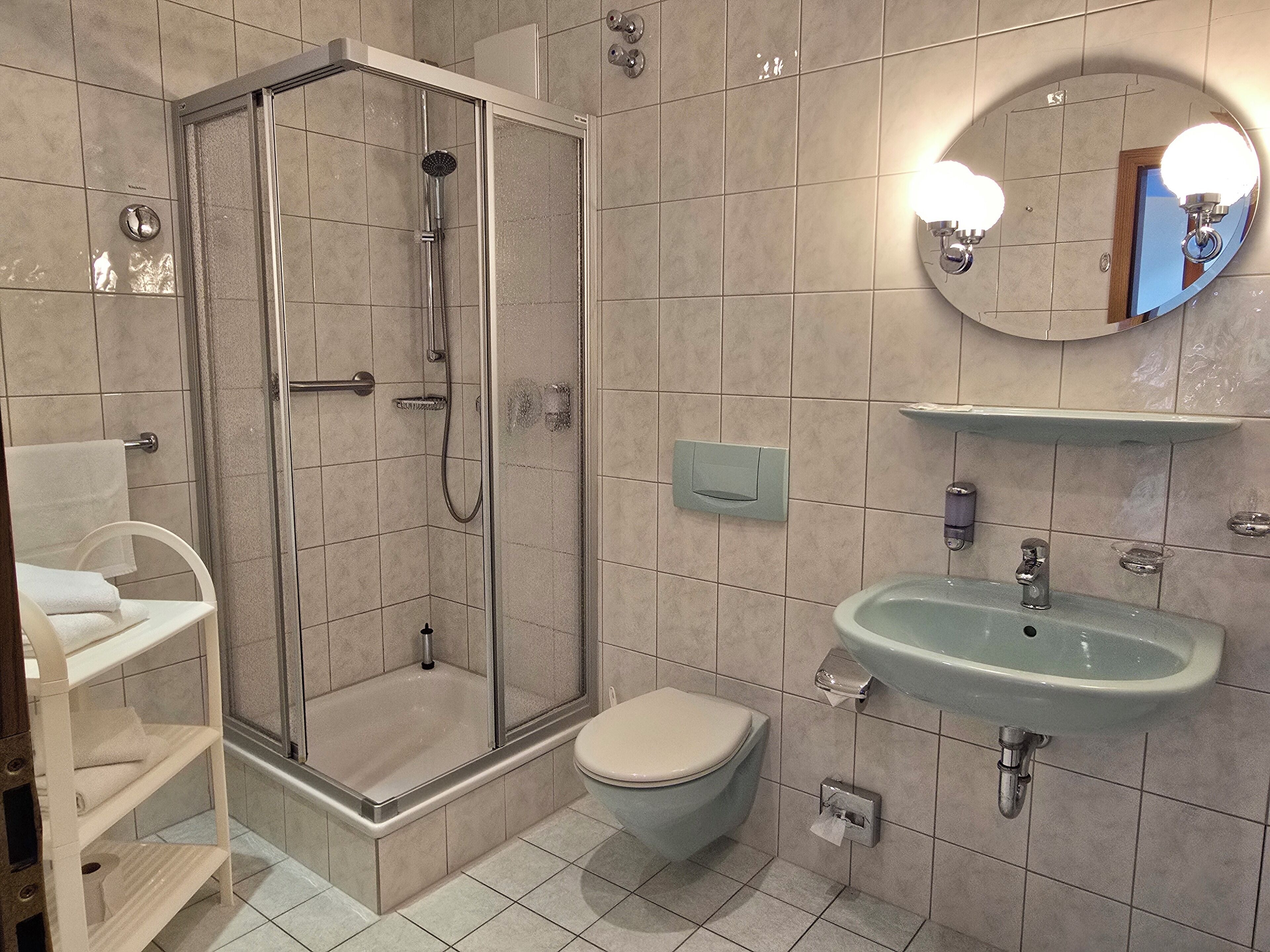 Un baño con ducha de mampara de vidrio, inodoro, lavabo y espejo.