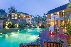 A pool area with a wooden deck, lounge chairs, and a dining setup with umbrellas. - Anulekha Resort and Villa (Ubud)