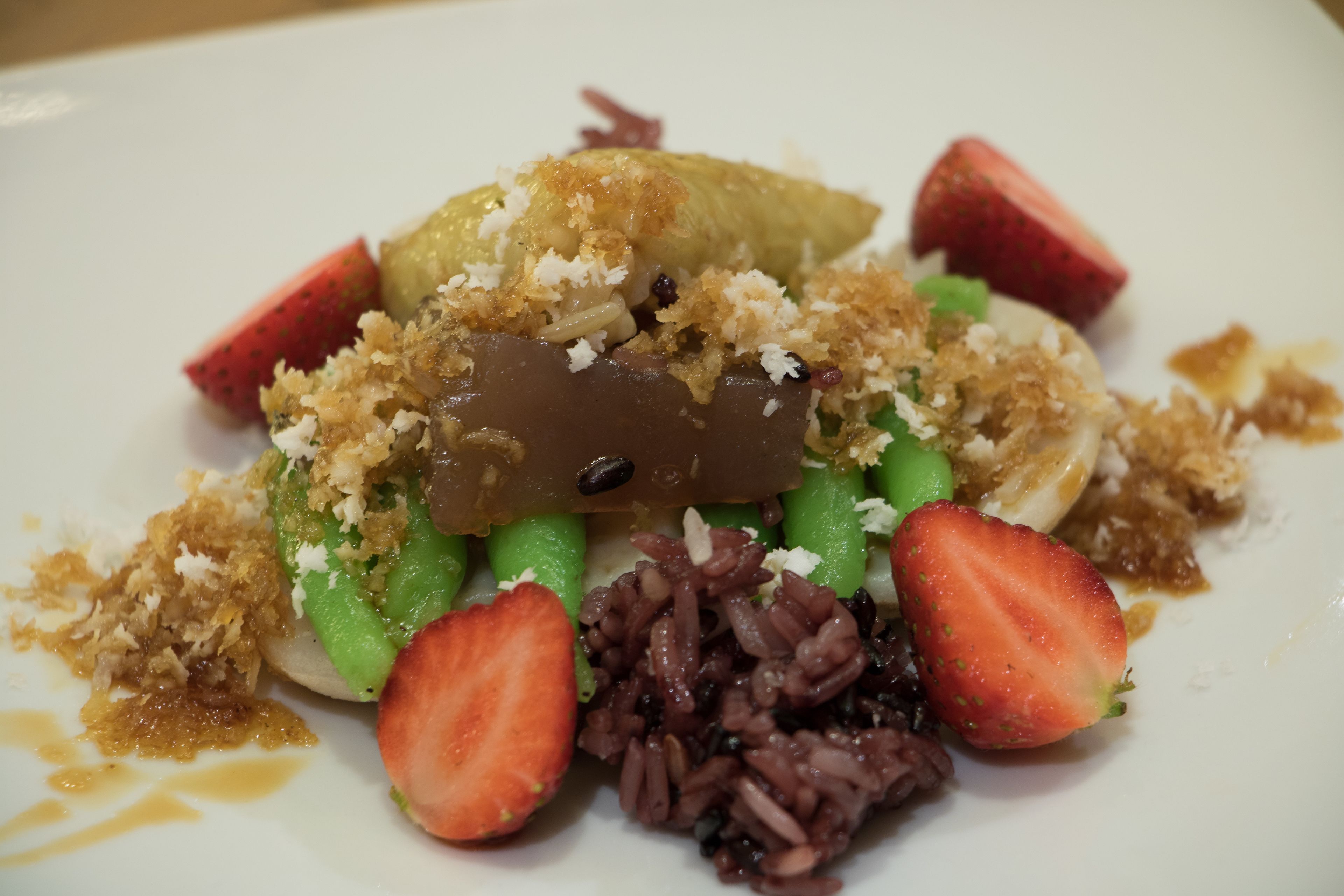 A dessert plate with various fruits and a chocolate piece.