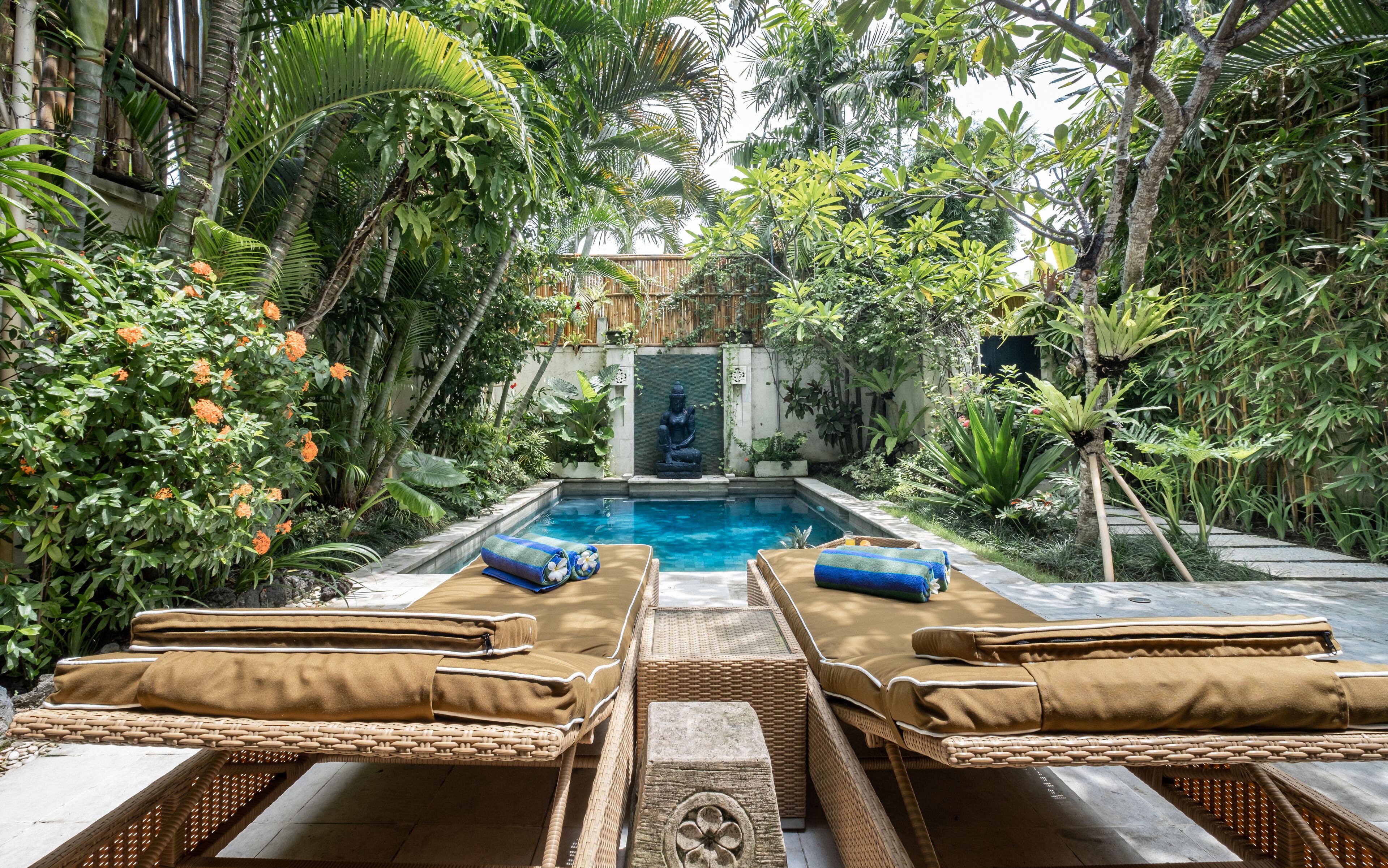 A pool area with lounge chairs and a statue.