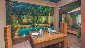 An outdoor dining area with a pool, bamboo plants, and candles. - Villa Seriska Seminyak Bali (Seminyak)