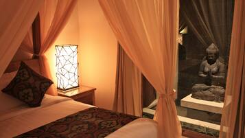 A bed with a patterned bedspread, a bedside lamp, and curtains.