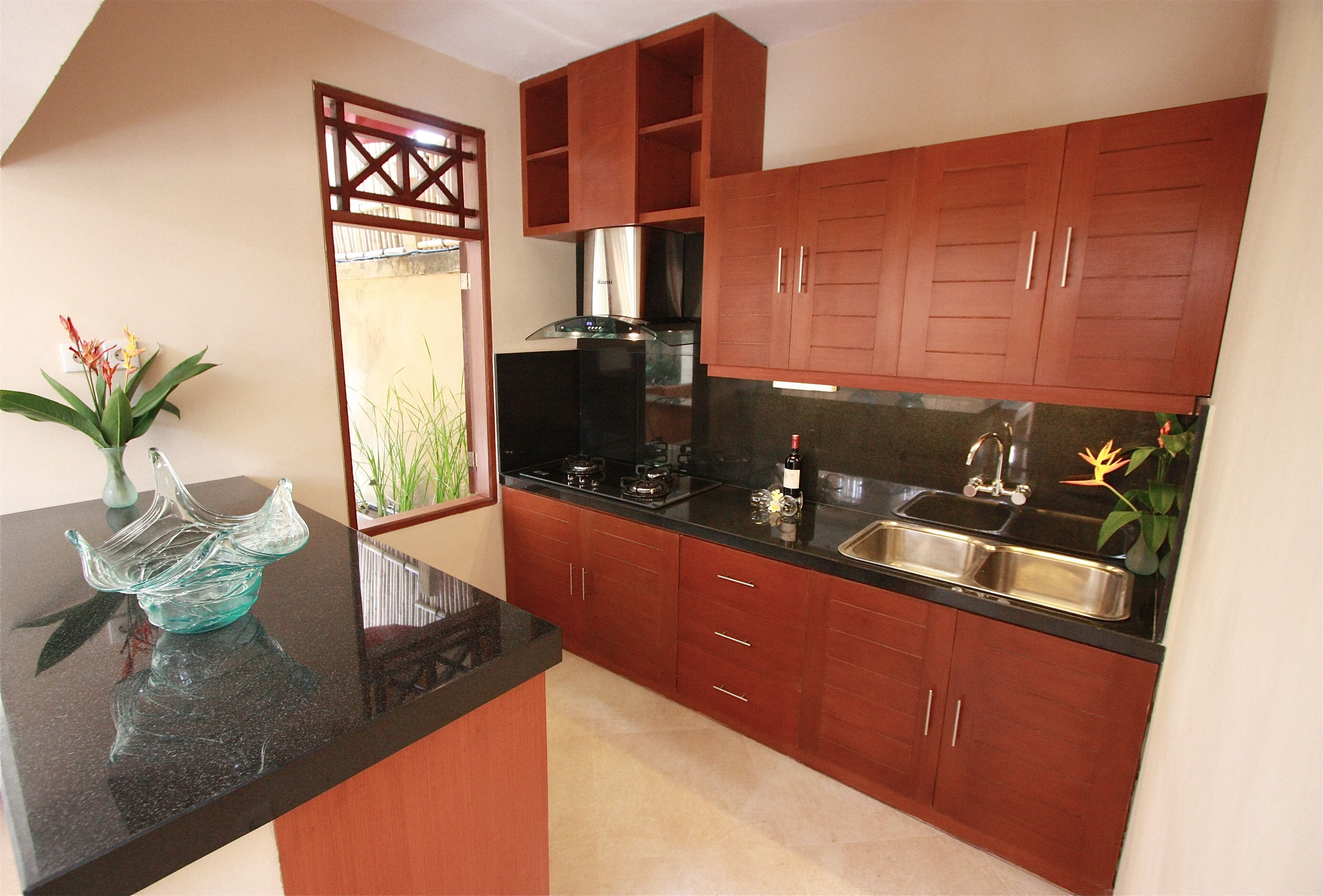 A kitchen with wooden cabinets, a black countertop, a stainless steel sink, and a coffee maker.