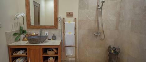 A bathroom with a wooden vanity, a large mirror, a bowl sink, a shower, and a bathtub.