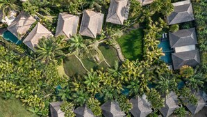 An aerial view of a resort with multiple bungalow-style buildings, a central swimming pool, and lush tropical landscaping. - The Sankara Resort & Spa (Ubud)