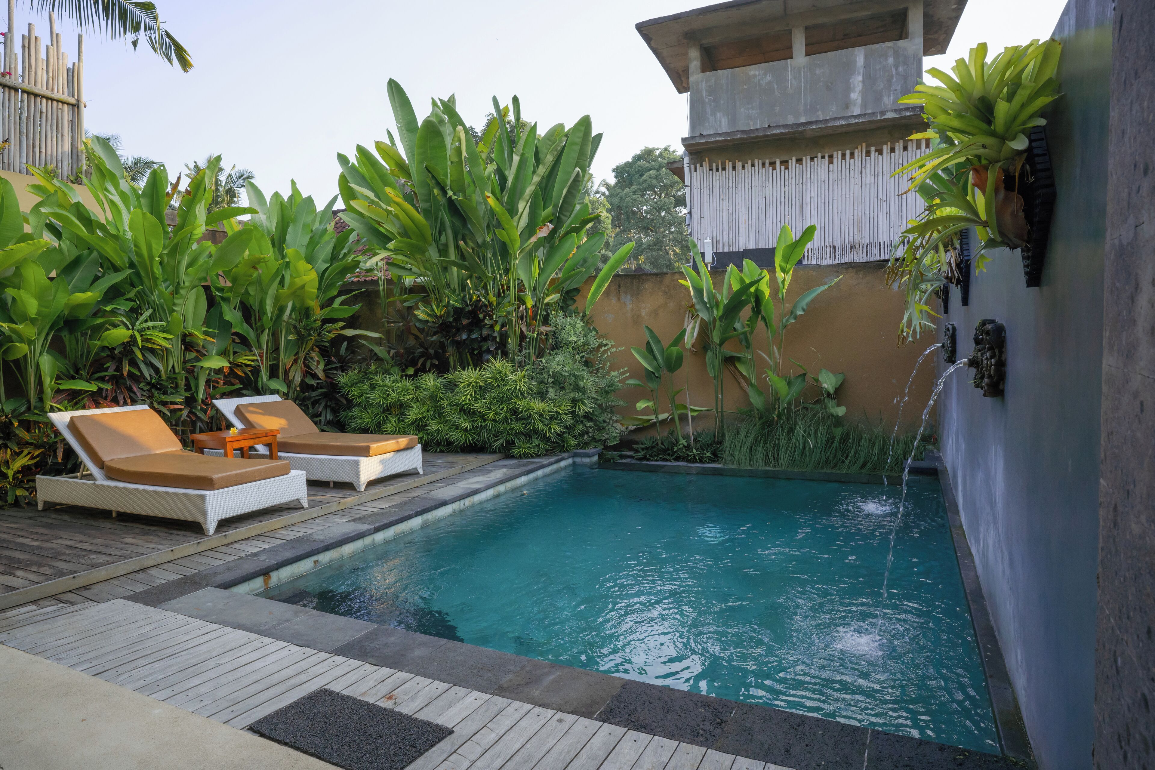 Un espace piscine doté de chaises longues et d’une petite cascade décorative.