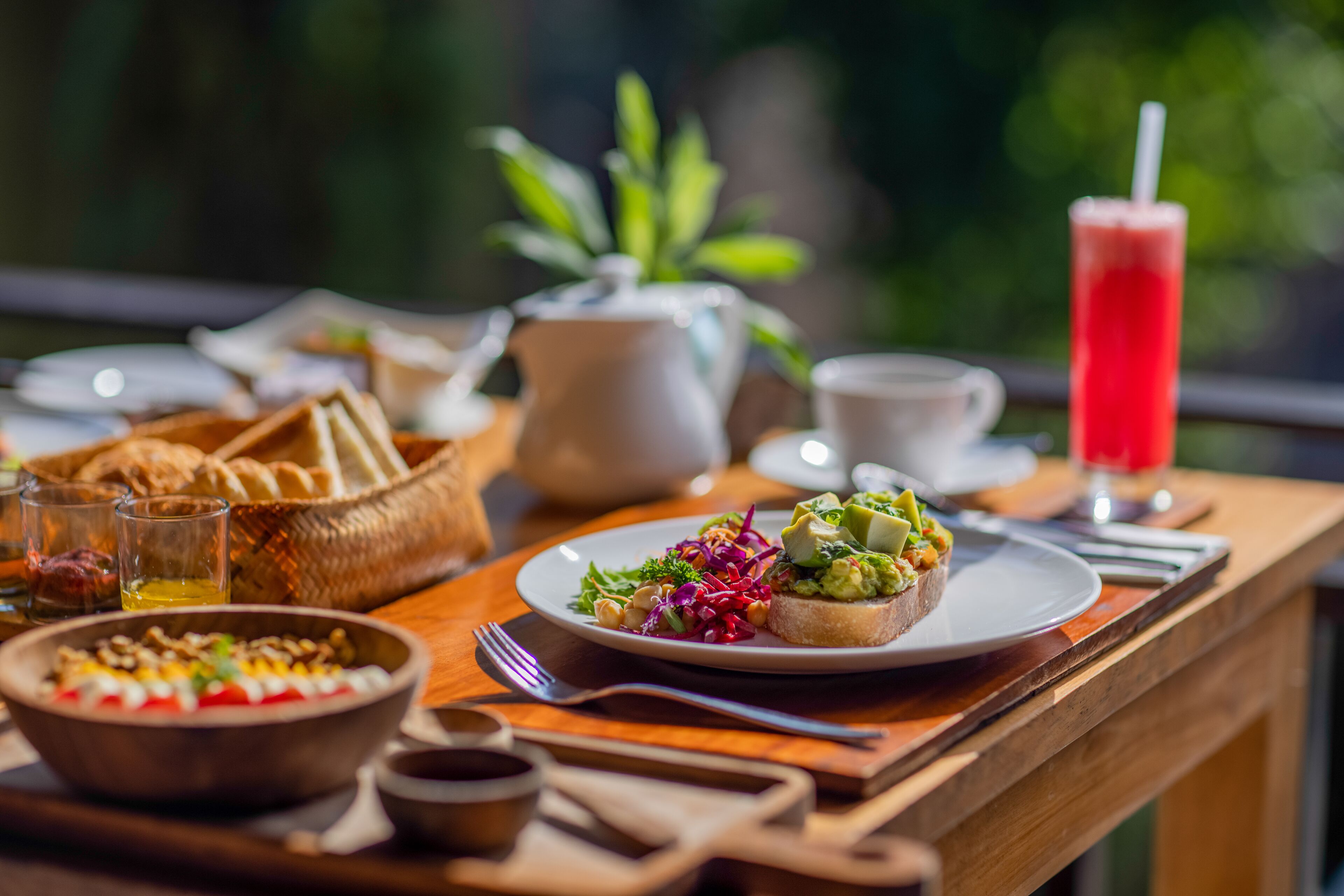 A table with a plate of food, a pitcher, glasses, and a tall drink.