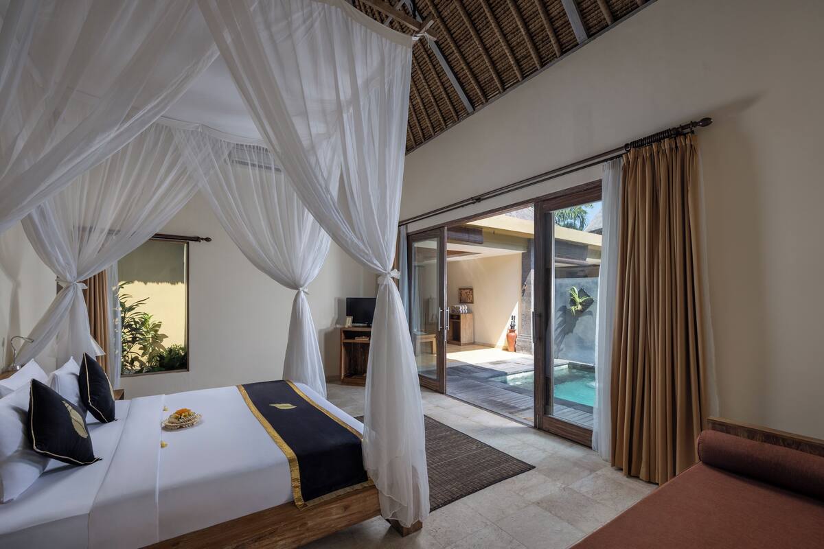 A bedroom with a bed, a TV, and a view of an outdoor area.