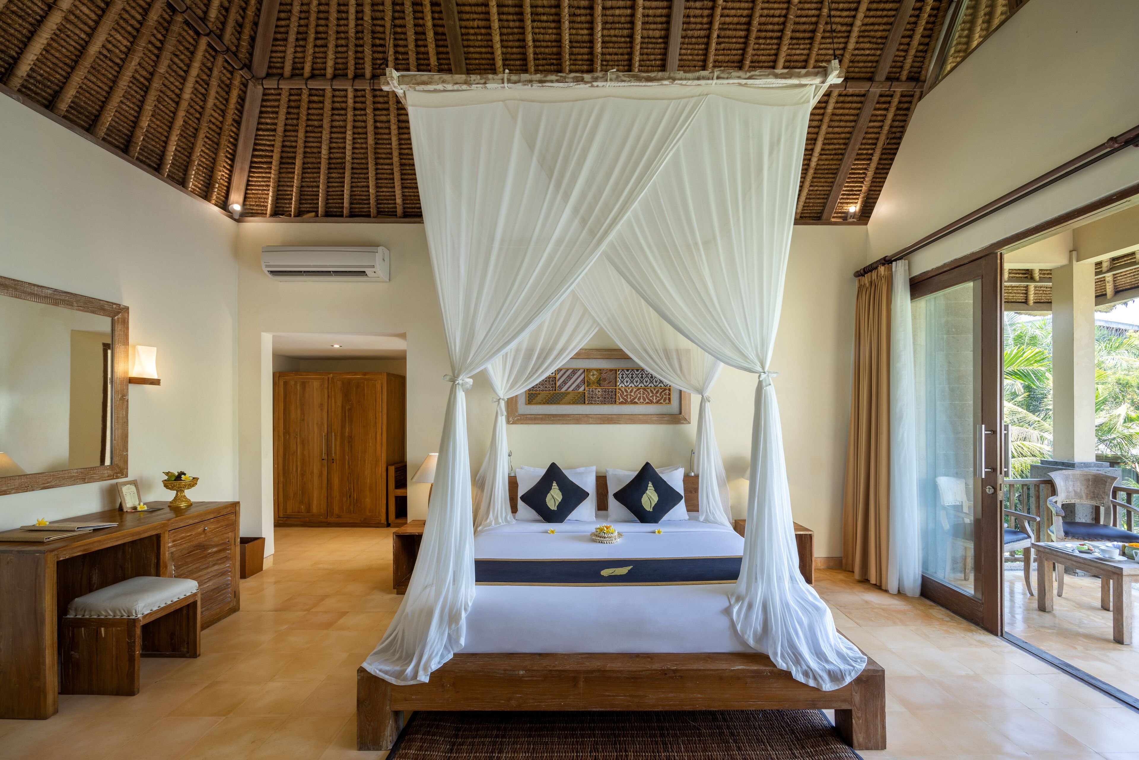 A bedroom with a four-poster bed, wooden furniture, and a view of the outdoors.