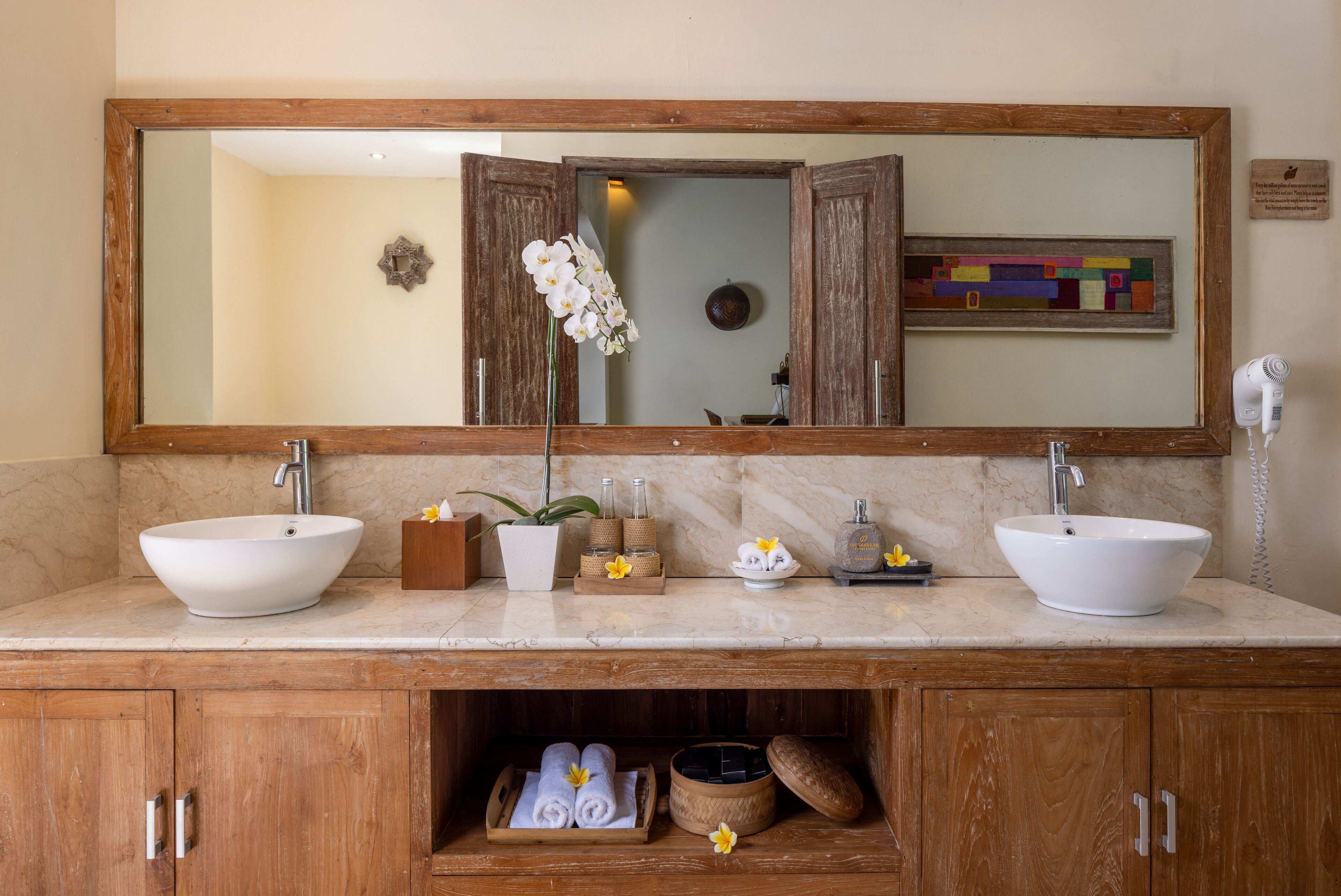A bathroom with two sinks, a large mirror, and wooden cabinets.