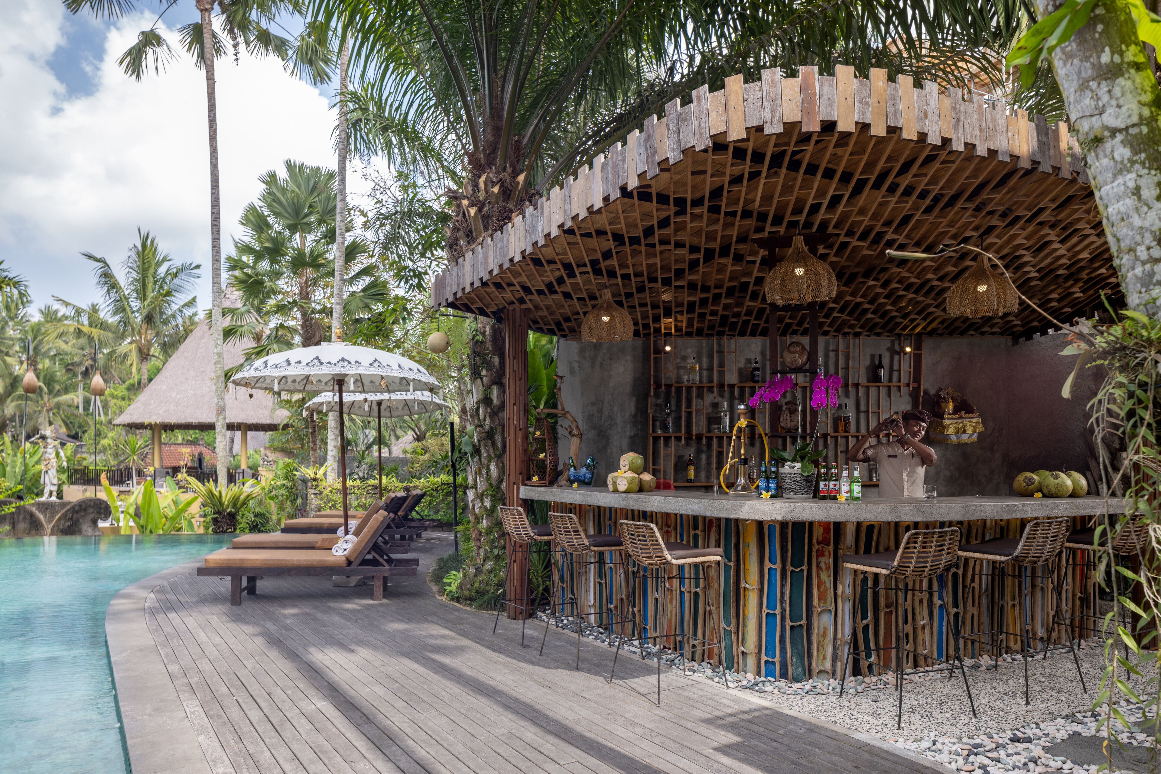 A wooden deck with lounge chairs and a bar area with stools.