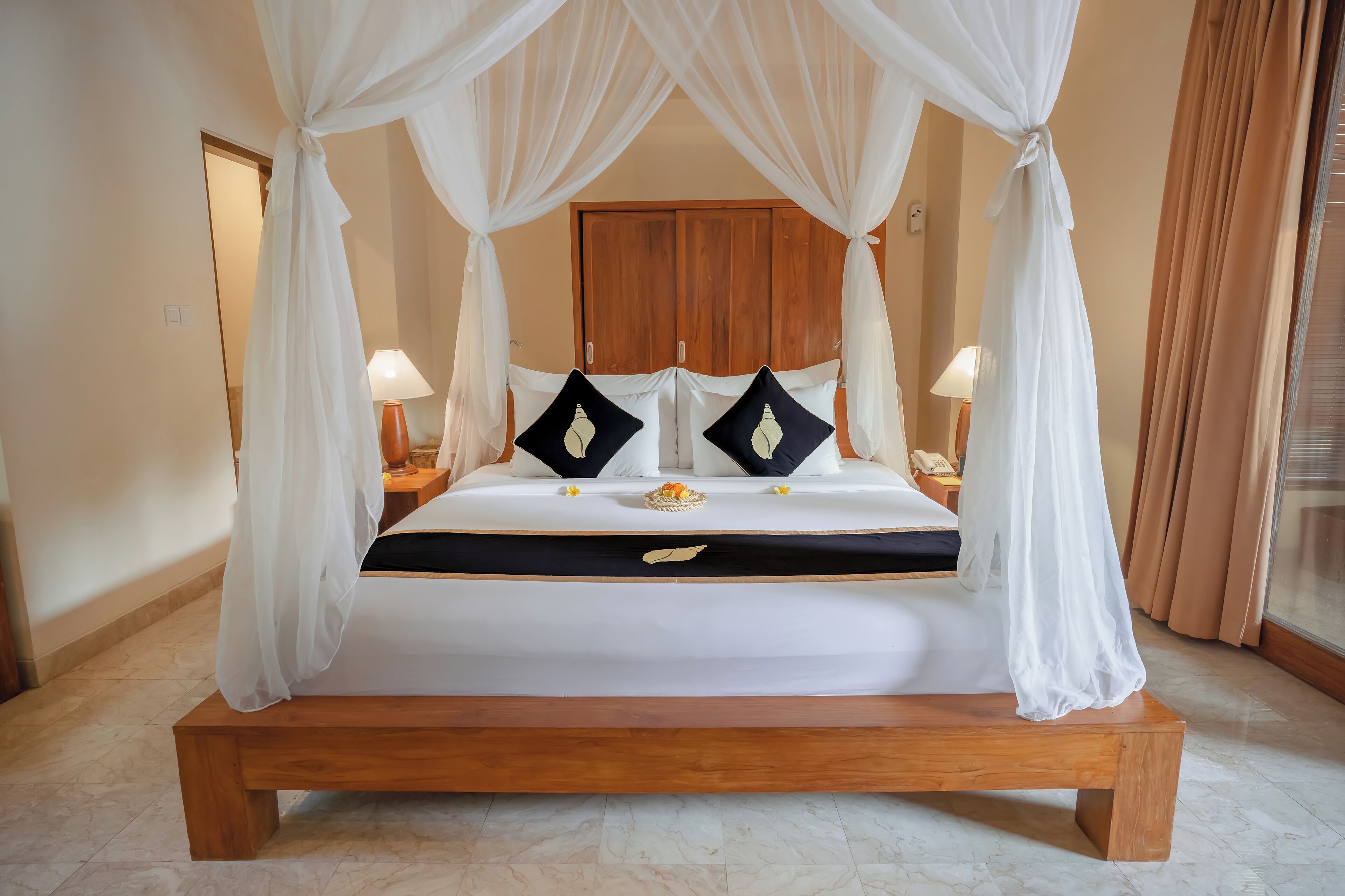 A bed with a canopy, bedside lamps, and a wooden headboard.