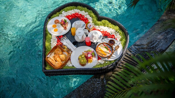 A heart-shaped table with various breakfast items and drinks, placed on a clear blue poolside. - The Sankara Resort & Spa (Ubud)