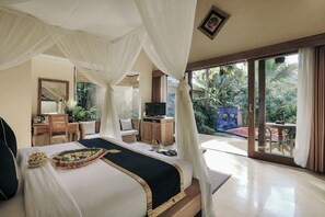A spacious bedroom with a large bed, a television, and a balcony with a view of tropical plants. - The Sankara Resort & Spa (Ubud)