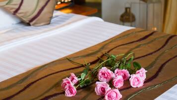 A neatly made bed with a striped pillow, a decorative wall panel, and a bedside table with a lantern.