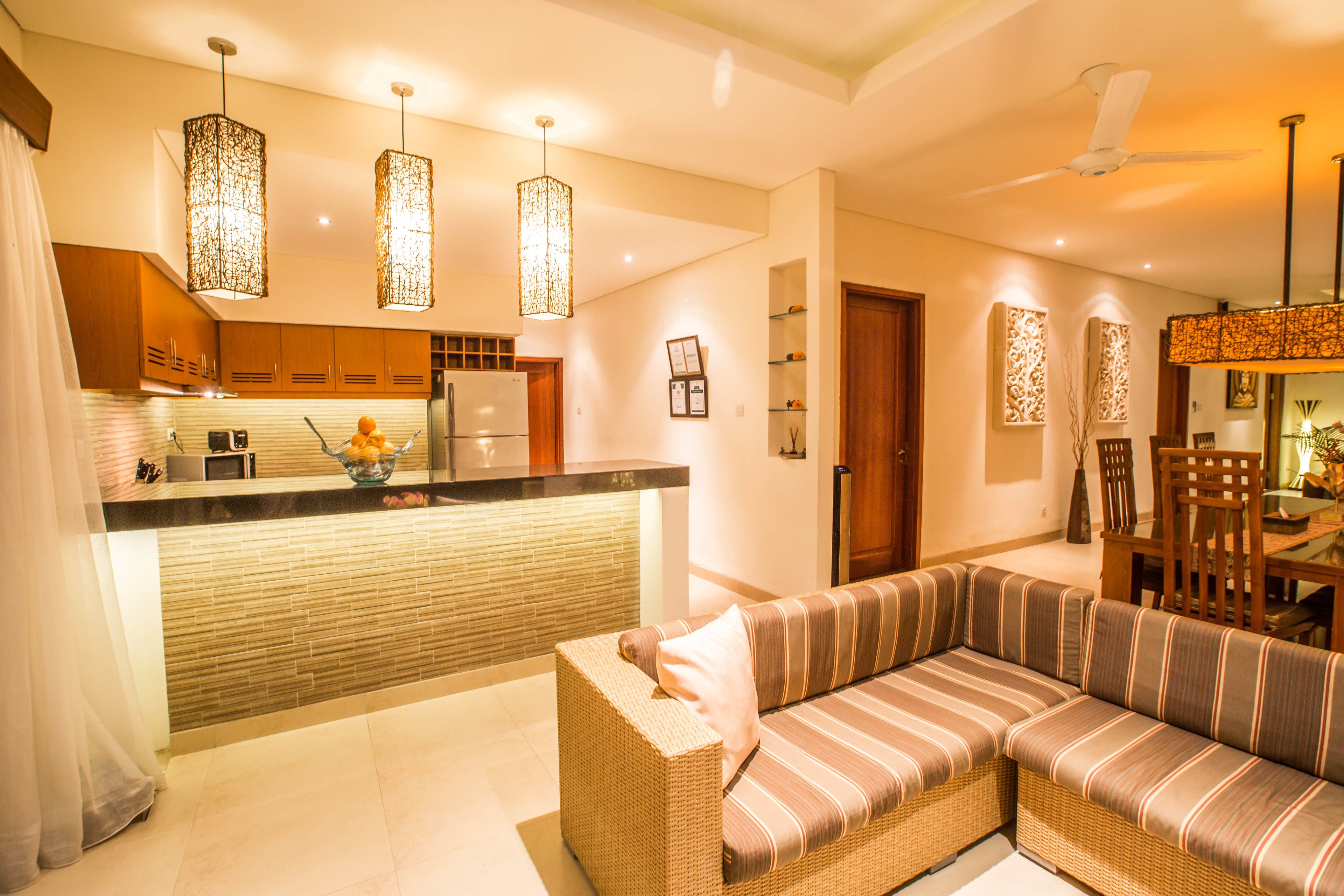 A modern kitchen with a built-in island, pendant lighting, and a dining area with a wooden table and chairs.